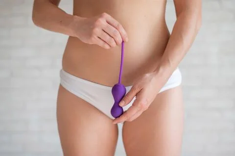 Faceless woman in white panties and with a bare tummy holds a kegel trainer Stock Photos