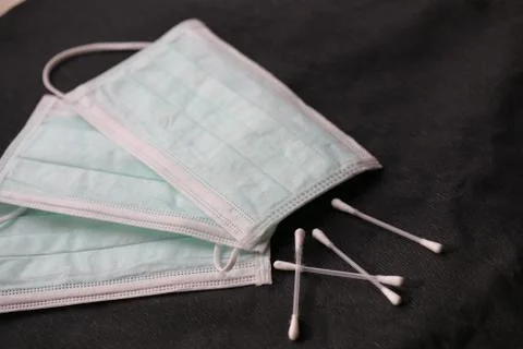 Facemasks with cottonbuds on a black surface Stock Photos