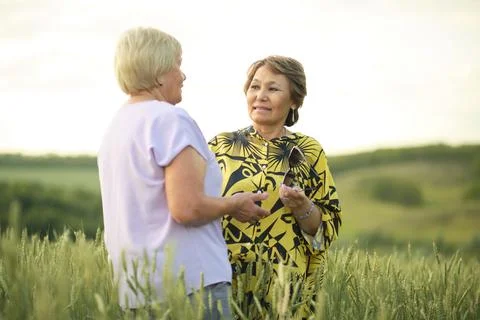 Faces aglow with the evening light, two women connect; their interaction a dance Foto stock