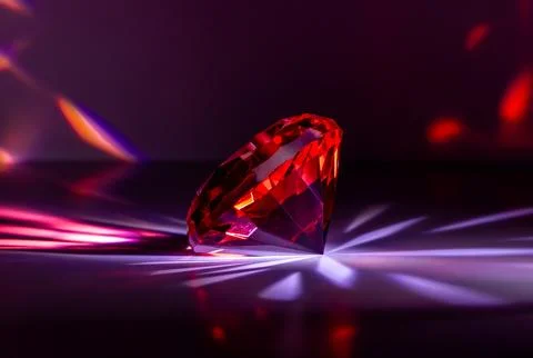 A faceted, bright red gemstone on a black background Stockfoto's