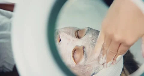 Facial Mask Application at Spa Through Magnifying Glass Stock Footage 323603084
