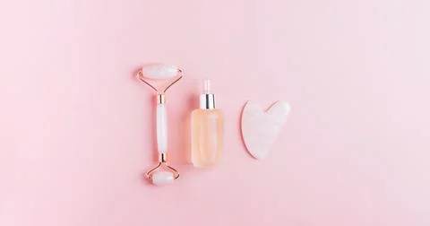 Facial massage set roller scraper guasha pink background. Stock Photos