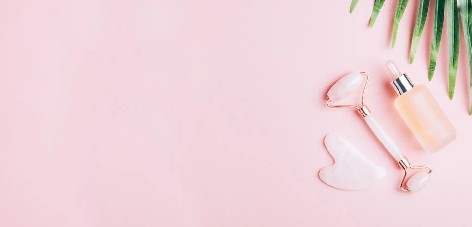 Facial massage set roller scraper guasha pink background. Stock Photos