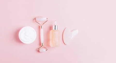 Facial massage set roller scraper guasha pink background. Stock Photos