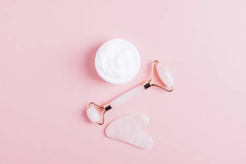 Facial massage set roller scraper guasha pink background. Stock Photos