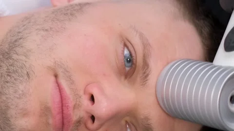 Facial massage of a young attractive man using a modern electric massager Stock Footage 250356419
