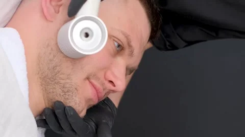 Facial massage of a young attractive man using a modern electric massager Video stock 250356505