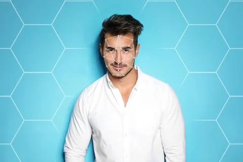 Facial recognition system. Young man with digital biometric grid on blue back Stock Photos