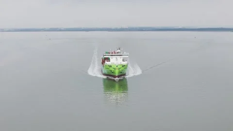 Facing bright green container ship advancing steadily across reflective water Stock Footage 328204429