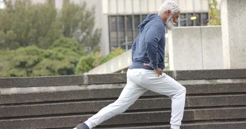 Facing plaza ledge, senior African American man stepping up for exercise, Stock Footage 317769502