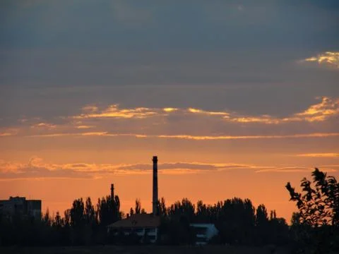 Factory on a background of orange cloudy sunset. Stock Photos