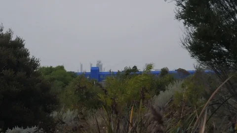Factory in the background surrounded by nature on an overcast day 4k Stock Footage 106392502