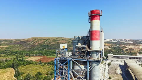 Factory building with a tall chimney and nearby fields under clear sky during Stock Footage 341388671