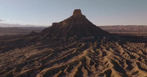 Factory Butte Above Rugged Desert Ridges Utah Aerial Pullback Video stock 333872878