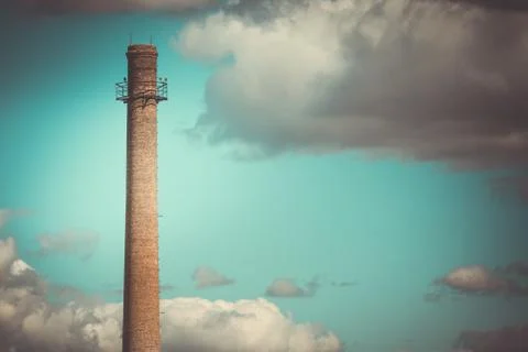 Factory chimney against the dramatic sky background Stock Photos