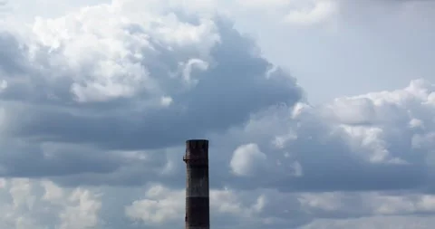 Factory chimney against saturated voluminous huge clouds timelapse Stock Footage 252079315