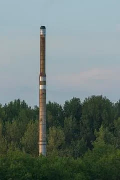 Factory chimney in a green environment. Stock Photos