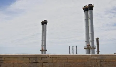 Factory chimneys above brick wall. Фото
