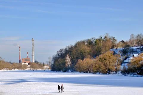 Factory chimneys on background of winter blue sky and frozen river Stock Photos