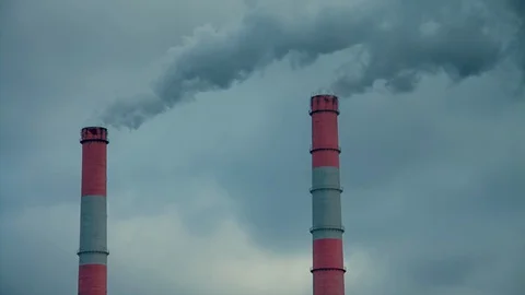 Factory chimneys emit smoke against a gray sky Stock Footage 128906892