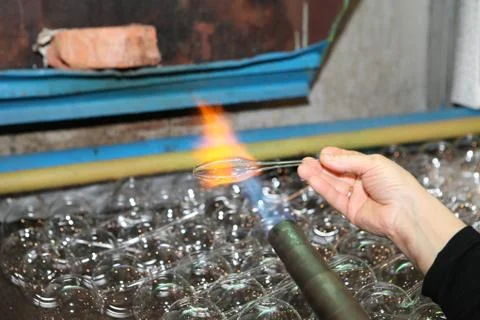 Factory of Christmas toys. The worker blows out the glass. The b Stock Photos