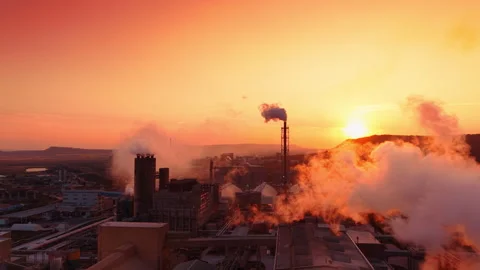 Factory complex releasing vapor into the air with a setting sun background. Wide Stock Footage 346006500