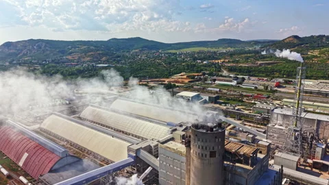 Factory complex in a rural area with smoke and clouds in the sky during daytime Stock Footage 341381933