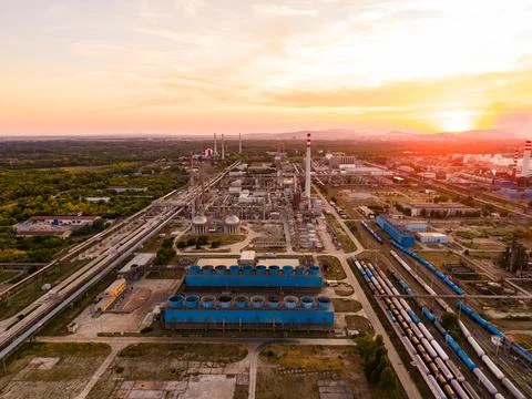 A factory complex is seen at sunset with large tanks and facilities. Trains t Stock Photos