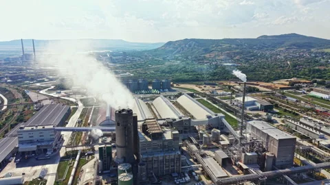 Factory complex with smoke rising from chimneys in a rural area near a city Stock Footage 341703196