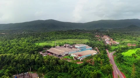Factory in dense forest beside a highway cutting through green mountain terrain Vídeo Stock 340974992