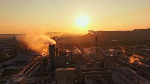 Factory emits smoke during sunset with a view of mountains in the background and Stock Footage 341702998