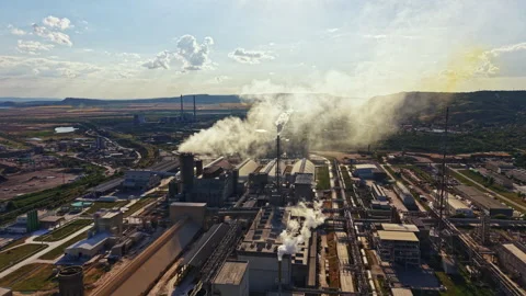Factory emitting smoke in a rural area during the day with machinery and fields Stock Footage 340962283