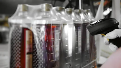 A factory employee uses a scanner to mark packaging of bottles with a drink. Stock Footage 288411157