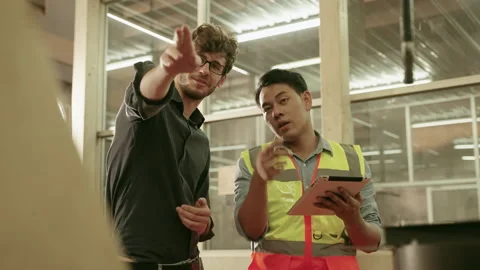 The factory engineer is explaining the operation of the machine to the foreman. Stock Footage 153863165
