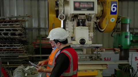 Factory engineer is inspecting the operation of the machines inside Stock Footage 214451300