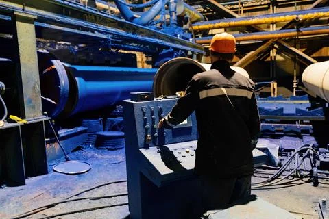 Factory engineer operates pipe painting automatic machine Stock Photos