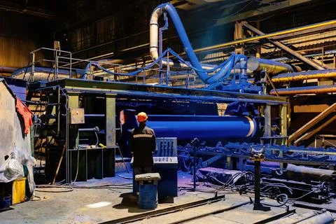 Factory engineer operates pipe painting automatic machine Stock Photos