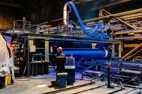Factory engineer operates pipe painting automatic machine Stock Photos
