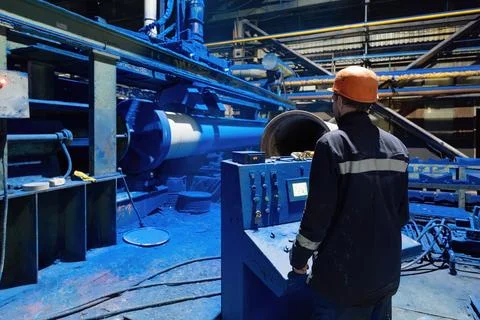 Factory engineer operates pipe painting automatic machine Stock Photos