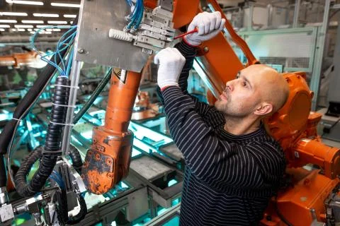Factory engineer operating with automatic robot arms in automotive industry Stock-Fotos
