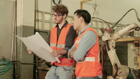 Factory engineers are discussing and explaining the operation of the robotic arm Stock Footage 154187469