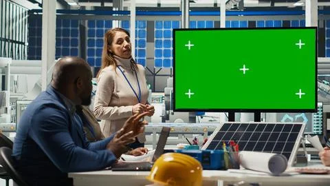Factory engineers look over schematics during meeting in front of mockup monitor Stock Photos