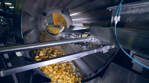 Factory equipment rotates crisps in a machine, adding flavor enhancers. Stock Footage 105596677