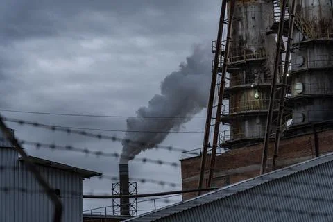 The factory features a tall structure with a brick exterior and rusted supports Фото