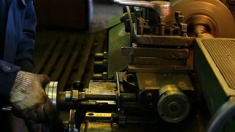In the factory, a gloved worker controls the lathe in which the workpiece is pro Stock Footage 128603768