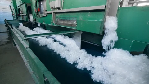 Factory machines work with white polyester fiber, moving it onto a conveyor. Stock Footage 107904529