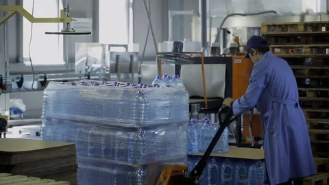 At factory man in uniform moves bottled water on trolley. Stock Footage 81010105