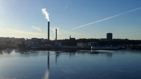 Factory in the middle of a city causing air pollution near water Stock Footage 75044438