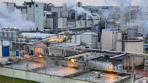 Factory with multiple smoking stacks, illuminated by yellow lights, a symbo.. Stock-Footage 260382020