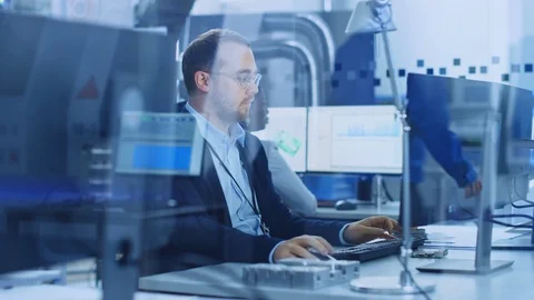 Factory Office: Industrial Engineer working on PC, On his Desk Blueprints Stock Footage 123635123